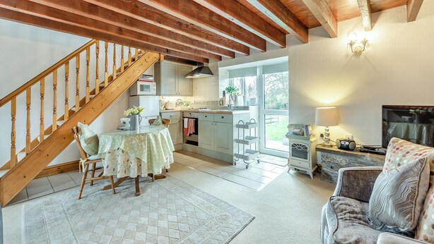 A cozy kitchen with wooden beams, a dining area with a table and chairs, and a living room with a sofa and a fireplace. - 0 bedroom accommodation in Gowerton, Gower (Gowerton, Gower)