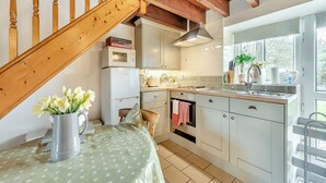 A kitchen with white cabinets, a stove, and a sink. There is a wooden staircase leading to another level. - 0 bedroom accommodation in Gowerton, Gower (Gowerton, Gower)