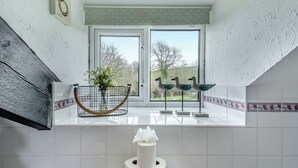 A bathroom with a toilet, a window with a view of trees, and a decorative bird sculpture. - 0 bedroom accommodation in Gowerton, Gower (Gowerton, Gower)