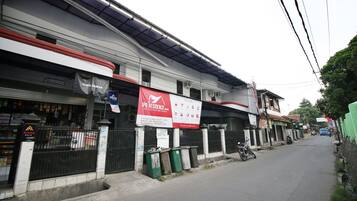A street view with a building featuring a red banner advertising a residential property.