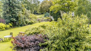 A lush garden with a variety of trees and shrubs, a grassy lawn, and outdoor seating. - 2 bedroom accommodation in West Burton, near Leyburn (West Burton, near Leyburn)