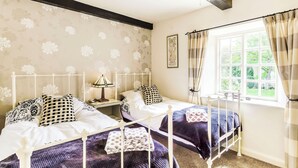 A bedroom with two beds, a nightstand, a lamp, and a window with curtains. - 2 bedroom accommodation in West Burton, near Leyburn (West Burton, near Leyburn)
