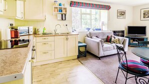 A compact kitchen with a microwave, toaster, and stove. There's a dining area with a sofa and a TV. - 2 bedroom accommodation in West Burton, near Leyburn (West Burton, near Leyburn)