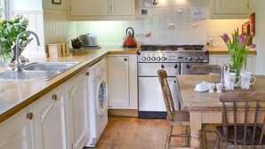 Une cuisine équipée d’une cuisinière, d’un évier et d’un lave-linge.