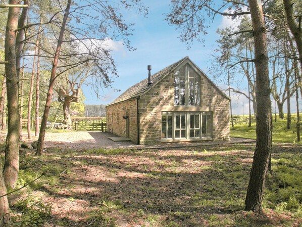 A stone building with a gabled roof, large windows, and a gravel path leading to it.
