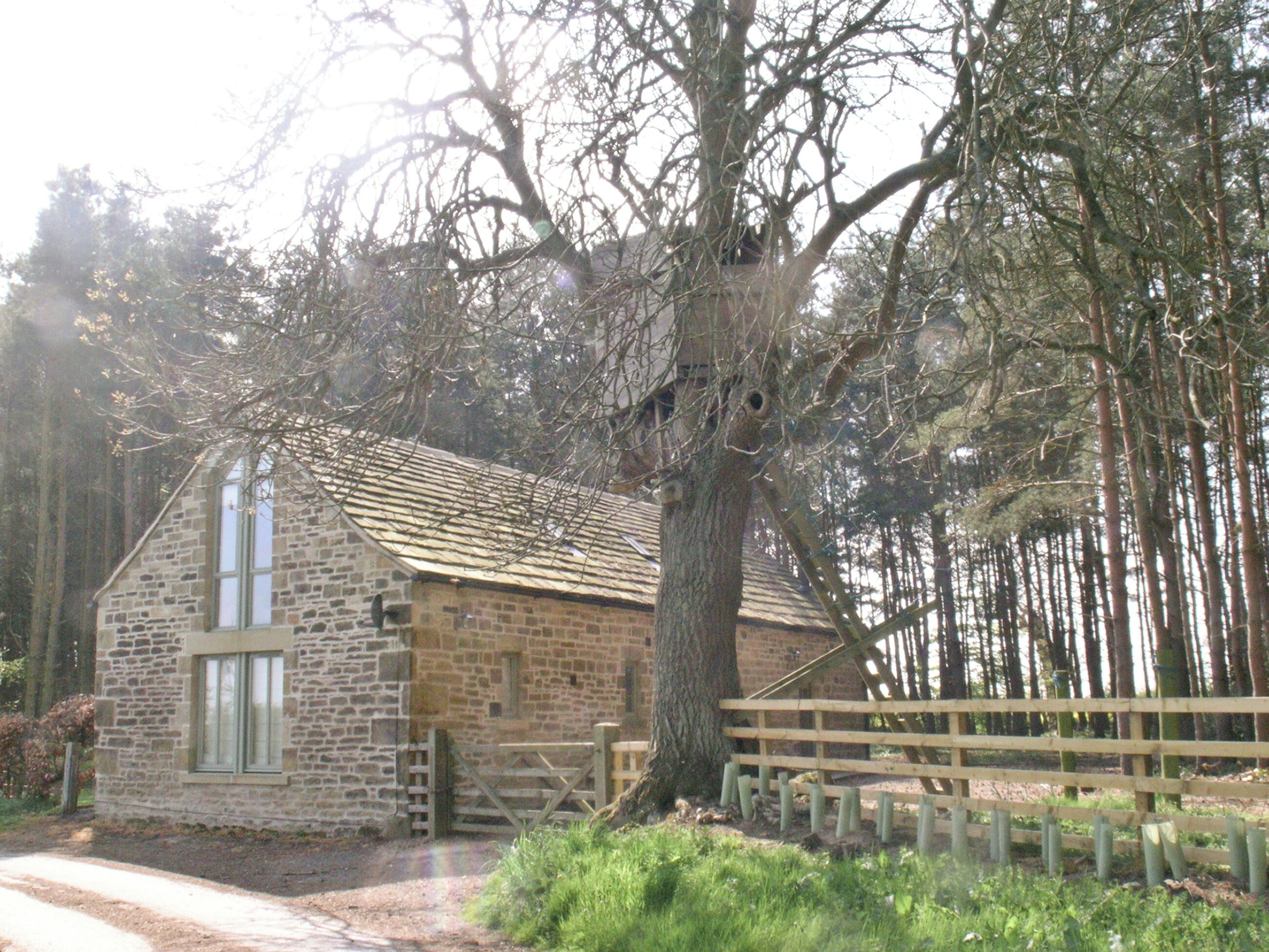 Un edificio de piedra con techo inclinado, una puerta de madera y un área cercada.