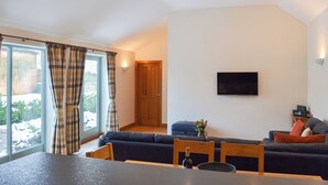 A modern living room with a sofa set, a dining table, and a TV mounted on the wall. - 3 bedroom accommodation in Spaunton, near Lastingham (Spaunton, near Lastingham)