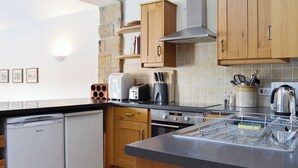 A modern kitchen with wooden cabinets, a stone accent wall, a built-in oven, a dishwasher, and a coffee maker. - 3 bedroom accommodation in Spaunton, near Lastingham (Spaunton, near Lastingham)