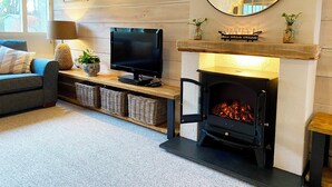 Ein gemütliches Wohnzimmer mit Kamin, Fernseher und einer bequemen Couch.