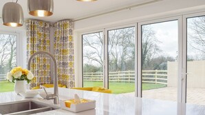 A modern kitchen with a large window, a sink, and a yellow chair. - 3 bedroom accommodation in New Moat, near Narberth (New Moat, near Narberth)