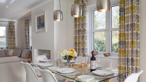A dining area with a glass table, white chairs, and pendant lights. - 3 bedroom accommodation in New Moat, near Narberth (New Moat, near Narberth)