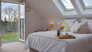 A bedroom with a skylight, a bed with white bedding, a bedside table with a lamp, and a tray with breakfast items. - 3 bedroom accommodation in New Moat, near Narberth (New Moat, near Narberth)
