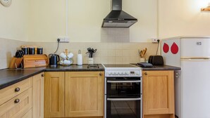 A kitchen with wooden cabinets, a stove, oven, and a white refrigerator. - Granary Cottage - E5634 (Chittlehampton, near Umberleigh)