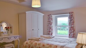 Un dormitorio con cama, cómoda, espejo y ventana con cortinas.