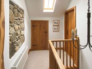 A hallway with a stone wall, wooden door, and a small window. - 3 bedroom accommodation in Treffynnon, near St Davids (Treffynnon, near St Davids)
