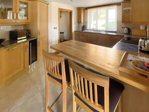 A modern kitchen with wooden cabinets, a central island, and a dining area with two chairs.