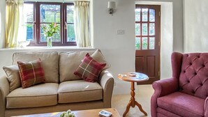 Ein Wohnzimmer mit einem beigefarbenen Sofa, einem roten Sessel, einem Holztisch und einem kleinen Beistelltisch.