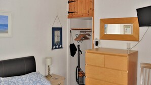 Une chambre à coucher avec un lit, une commode, un miroir, une lampe et un aspirateur.