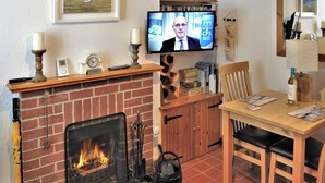 Un salon chaleureux avec une cheminée, un téléviseur, une bibliothèque et un coin repas.