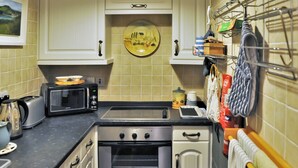 Une cuisine compacte équipée d’un grille-pain, d’un four à micro-ondes, d’un four traditionnel et d’un égouttoir à vaisselle.