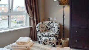 Une chambre avec une fenêtre, une chaise, une lampe et un lit avec des serviettes.
