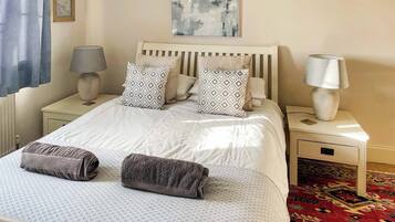 A neatly made bed with patterned pillows, a bedside lamp, and a rug.