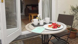 Eine offene Tür, die in einen Raum führt, in dem ein Esstisch mit Erdbeeren, zwei herzförmigen Tassen und einem kleinen Blumentopf gedeckt ist.