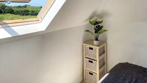 Ein Zimmer mit Dachfenster, einem Blumentopf und Weidenkorbmöbeln.
