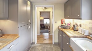 Une cuisine moderne avec des meubles gris, un plan de travail en bois et un sol carrelé.