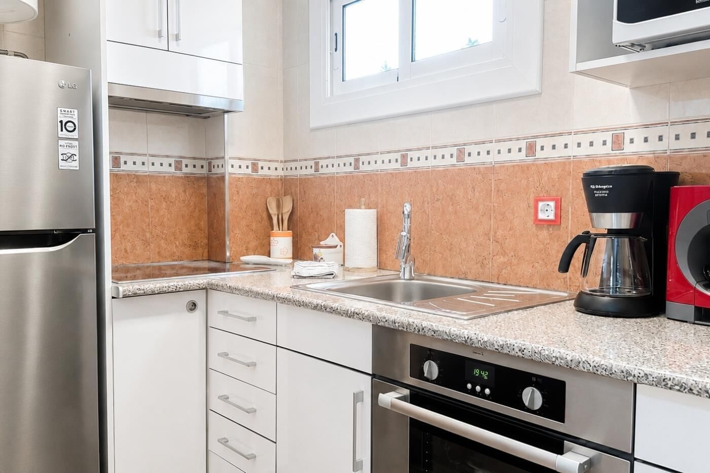 A modern kitchen with stainless steel appliances, a granite countertop, and a coffee maker.
