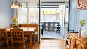 A dining area with a wooden table and chairs, a hanging light fixture, and a view of the outside balcony. - POOL TERRACE APARTMENT TOSSA DE MAR (Tossa de Mar)