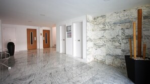 A spacious lobby with marble flooring, multiple doors, and a wall with a marble pattern. - POOL TERRACE APARTMENT TOSSA DE MAR (Tossa de Mar)