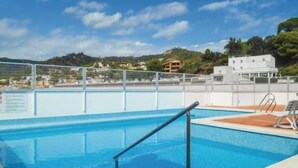 A swimming pool with a clear view of the surrounding landscape, including buildings and hills. - POOL TERRACE APARTMENT TOSSA DE MAR (Tossa de Mar)