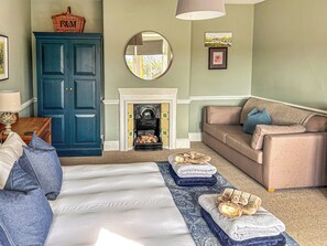 Una habitación con cama, sofá, chimenea, armario y espejo.