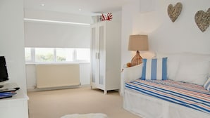 Un dormitorio con una cama, un escritorio, una lámpara y una alfombra de piel blanca.