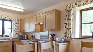 A kitchen with wooden cabinets, a stove, and a dining table with chairs.