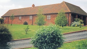 A brick building with a sloped roof, surrounded by a well-maintained lawn and a gravel path.