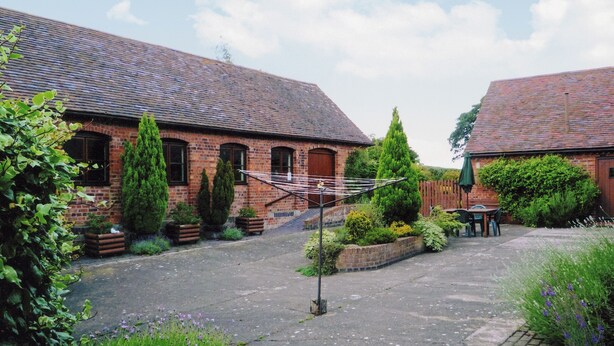 A courtyard with two brick buildings, a clothesline, and surrounding greenery.