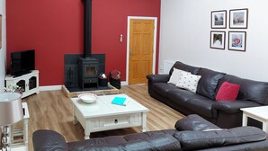 A living room with a fireplace, a sofa, a coffee table, and a television. - Peacock Barn - E5479 (Timberland, near Woodhall Spa)