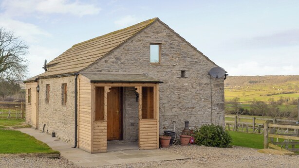 A stone building with a pitched roof, a wooden door, and a satellite dish.