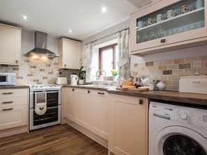 A modern kitchen with a built-in oven, microwave, and a washing machine.