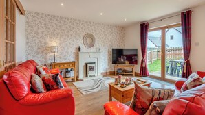 A living room with a red sofa, a fireplace, a television, and a view of the outside.