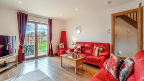 A spacious living room with a red sofa, a coffee table, and a TV.