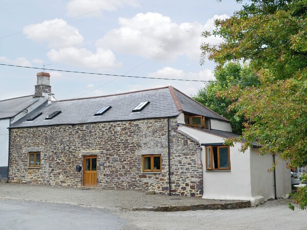 A stone house with a sloped roof, two windows, and a door.
