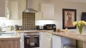 Een moderne keuken met een ingebouwde oven, een magnetron, een koffiezetapparaat en een broodrooster.