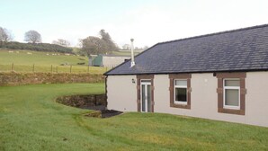 A single-story building with a dark roof and a white exterior. There is a small window and a door on the front. - Liftingstane Cottage (Closeburn, near Thornhill)