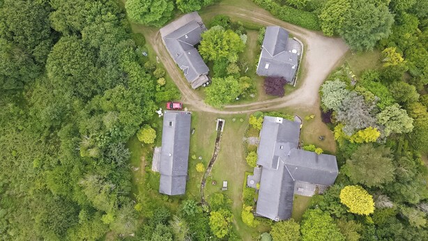 Vue aérienne d’un quartier résidentiel avec trois maisons, entouré d’une végétation luxuriante.