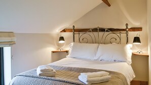 A neatly made bed with two pillows, a folded towel, and two bedside lamps. - 4 bedroom accommodation in Uggeshall, near Southwold (Uggeshall, near Southwold)