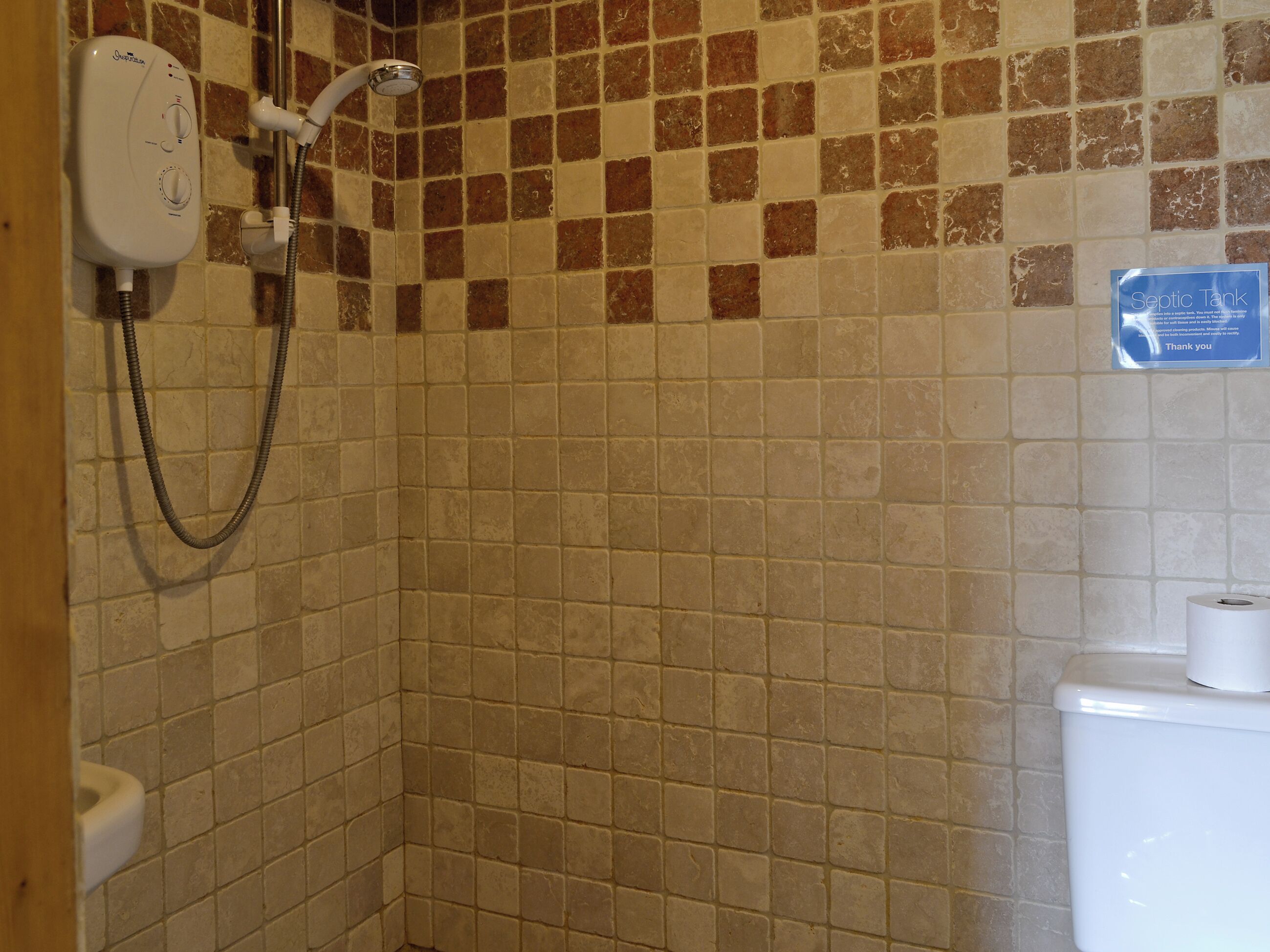 Un bagno con doccia, un water e un cartello che indica una fosse settica.