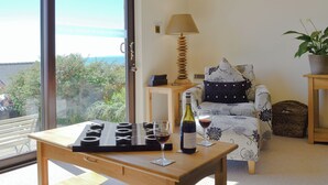 A cozy living room with a wooden table, a sofa with floral upholstery, a lamp, and a view of the outdoors. - 1 bedroom accommodation in Llanaber, near Barmouth (Llanaber, near Barmouth)